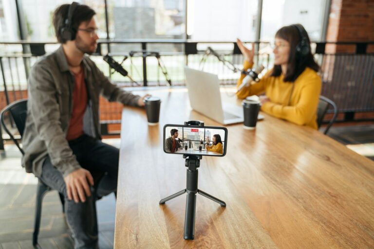 Two bloggers streaming live video podcast on smartphone in studio